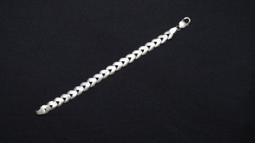 A silver-toned braided chain bracelet with a lobster clasp, displayed diagonally on a solid black background.