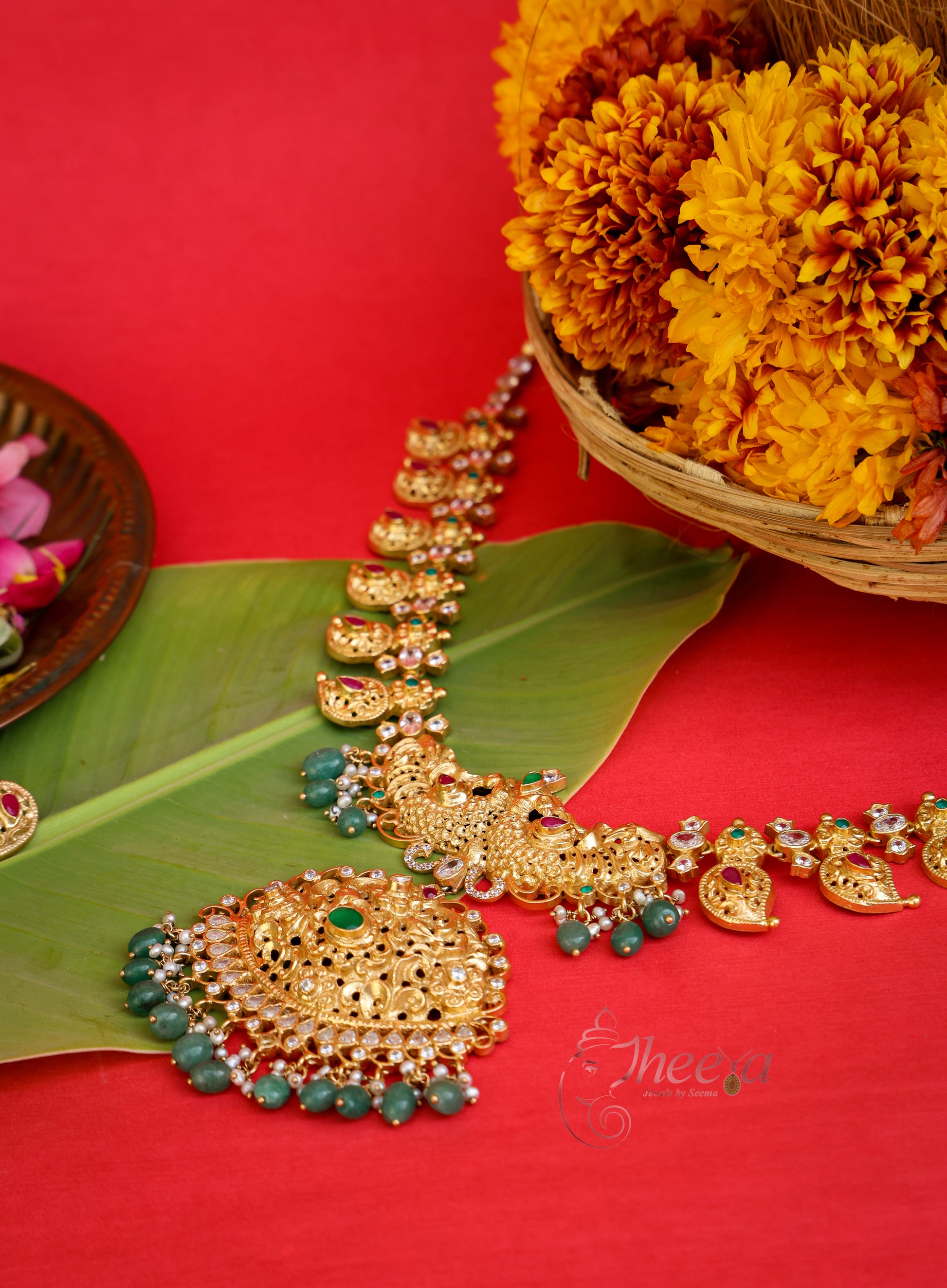 Close-up shot emphasizing the ornate central design and detailed green accent stones of the Kaveri Gold Antique Necklace
